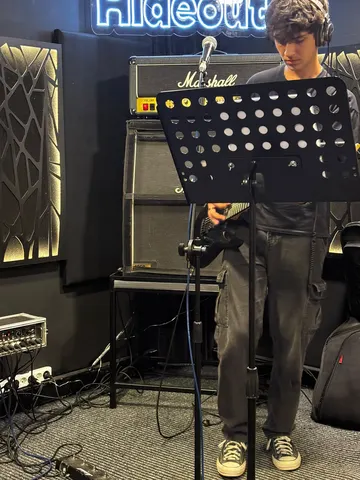 Hideout neon tabelası ve Marshall amfi önünde gitarist